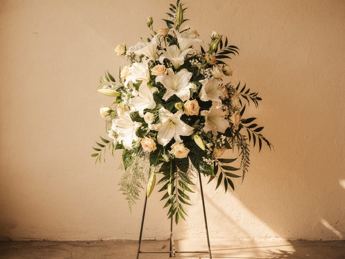 Standing sympathy spray of white lilies and cream roses for a funeral service